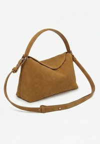 Sac à main en daim marron avec une poignée supérieure incurvée, une longue bandoulière réglable et une fermeture à rabat sur un fond uni.