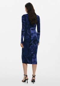 Pika-salong, keha järgi istuv kleit tumesinisena, millel on tekstuuriga lille- ja geomeetrilised mustrid; põlve pikkusega ja voolujoonelise siluetiga.