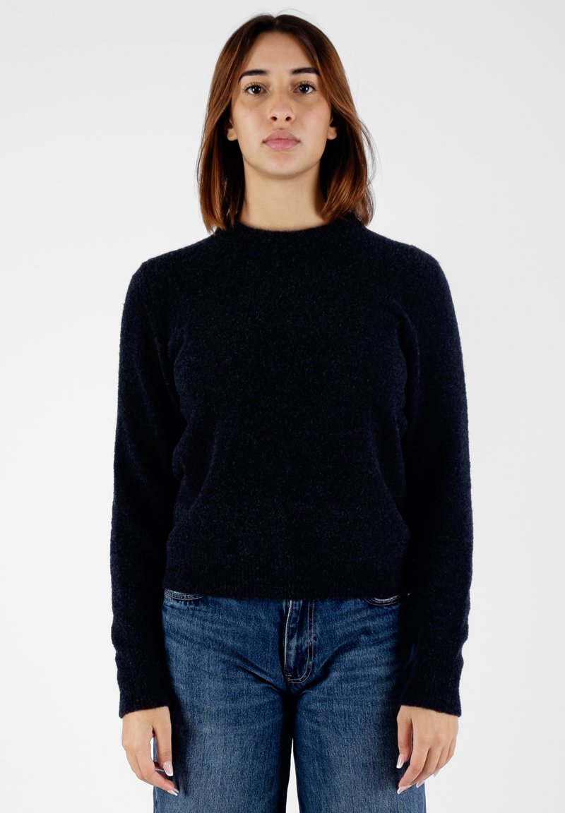 Maglione a maglia blu navy con scollatura rotonda e maniche lunghe. Tessuto morbido con un fit leggermente cropped, abbinato a jeans a vita alta.