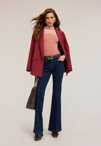 Maroon blazerin päällä vaaleanpunainen ribattutoppi, yhdistettynä tummansinisiin leveälahkeisiin farkkuihin. Asusteina musta vyö ja ruskea käsilaukku.