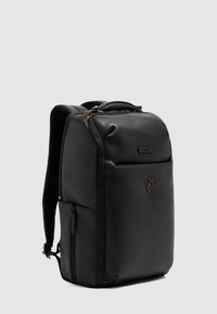 Mochila de cuero negro con superficie texturizada, que cuenta con un asa superior, correas ajustables y un logo discreto en el frente.