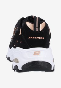 Baskets de sport noires avec une tige en daim texturé, accents en or rose, collier rembourré, et une semelle intermédiaire blanche avec un logo sur le talon.