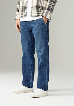 Blue denim jeans with straight legs, featuring a faded finish and five-pocket design, paired with white sneakers and a plaid shirt.