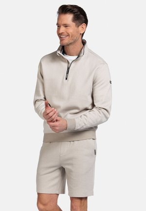 Lichtbeige zip-up sweatshirt met een gestreepte kraag, zachte textuur en elastische manchetten, gedragen met bijpassende shorts, ook in lichtbeige.