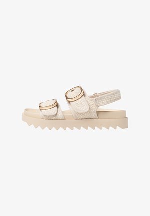 Beige Sandalen mit zwei großen Schnallenriemen, strukturiertem Obermaterial und cremefarbener, klobiger Sohle mit Zickzack-Kanten. Leichtes Design.