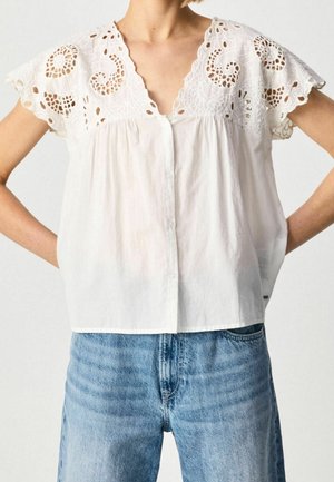 White cotton blouse with short, embroidered eyelet sleeves and a v-neckline, featuring a button front and a loose, relaxed fit.