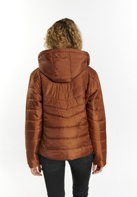Brun pufferjakke med hætte, med en horisontal quiltet design og tekstureret stof. Vist fra ryggen, parret med mørke jeans.