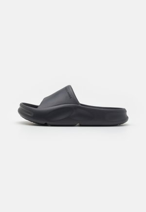 Sandale noire en plastique avec un design courbé et une texture en caoutchouc lisse. Dispose d'une sangle de soutien et d'une semelle rembourrée pour le confort.