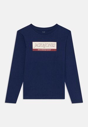 Tmavomodrá košeľa s dlhým rukávom so sloganom "JACK & JONES OD ROKU DEVÄTNÁSŤ" vytlačeným bielou a červenou farbou na hrudi.