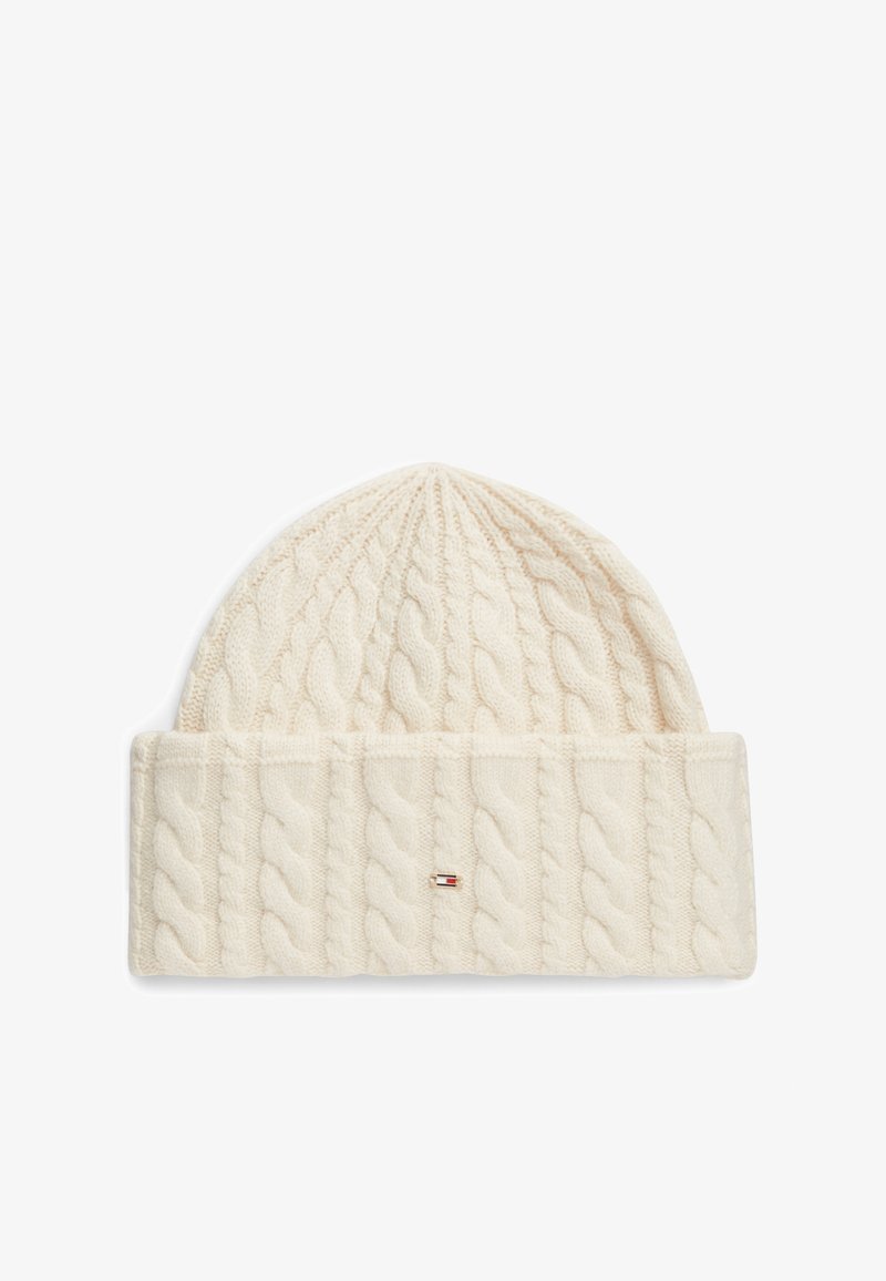 Bonnet en tricot couleur crème avec un large revers plié et un petit logo rectangulaire rouge, blanc et bleu à l'avant.