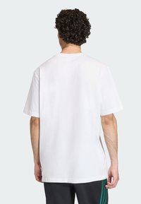 Άσπρο βαμβακερό μπλουζάκι με άνετη εφαρμογή, κοντά μανίκια και στρογγυλή λαιμόκοψη. Λεία υφή, απλό σχέδιο, χωρίς εμφανή γραφικά ή σχέδια.