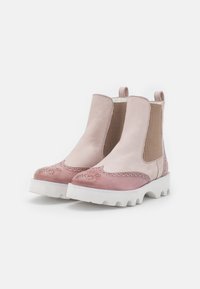 Růžové a béžové kožené kotníkové boty s elastickými bočními panely, detaily brogue a bílými chunky podrážkami. Kombinace hladkého a texturovaného povrchu.