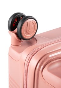 Rosa Hartschalenkoffer mit glatter Oberfläche, Doppelrollen und Reißverschluss. Bemerkenswerte Merkmale sind ein Steuerungsknopf und ein schlankes Design.