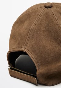 Cappello in suede marrone con visiera curva, dettagli cuciti e interno nero. Cintura regolabile sul retro. Superficie dalla texture liscia.