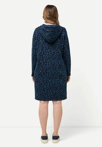 Kapuzenkleid in Marineblau mit Leopardenmuster. Lange Ärmel und knielanger Schnitt. Aus strukturiertem Stoff gefertigt. Lässiges Design.