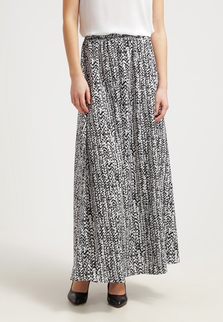 Maxikjol med elastisk midja, svartvit abstrakt mönster, svävande tyg, ihop med svarta skor, knälång.