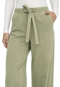 Pantalons larges vert clair en tissu doux, dotés d'une taille à cordon de serrage, de poches latérales et d'une coupe décontractée.