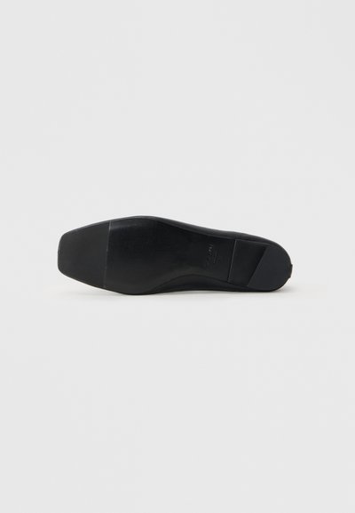 Semelle de chaussure en cuir noir avec une texture lisse et une forme légèrement pointue. Présente un accent strié près du talon et un fond plat.