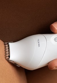 Witte, draadloze trimmer met een getextureerde grip, uitgerust met een zilveren snijblad. Toont het label 'Wet & Dry' en een symbool voor de aan-uitknop op de handgreep.