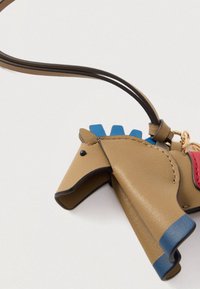 Καφέ δερμάτινο γούρι σε σχήμα αλόγου με μπλε χαίτη και οπλές, μαύρο μάτι και κόκκινη σέλα, προσαρτημένο σε λουράκι.