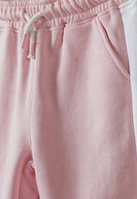 Rosa sweatpants i mjukt tyg, med resårmidja och dragsko, fickor på sidorna och vita sidostråk.