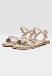 Sandalias de cuero rosa con diseño de tiras cruzadas, banda decorativa con patrones, suela plana y correa ajustable para el tobillo con acentos metálicos.