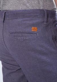 Námořnické texturované kalhoty s jemným vzorem, zadní kapsou a malou značenou koženou nášivkou. Klasický střih s rovnou siluetou.