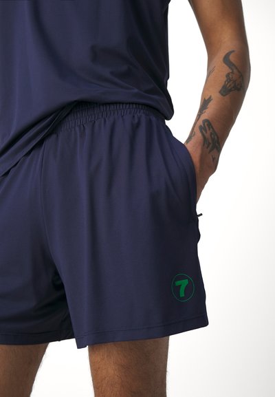 Marineblå treningsshorts laget av pustende stoff med en subtil tekstur. Har elastisk liv og en grønn, sirkelformet logo med nummer 7.