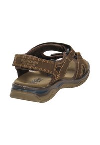 Brown leather sandal with adjustable straps, textured footbed, and sturdy rubber sole. Features contrast stitching and open heel design.