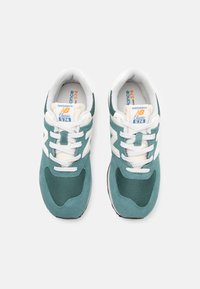 Tirkizno-bijeli New Balance tenisice od mrežice i antilopa, s podstavljenim jezikom, vezicama i klasičnim logotipom sa strane.