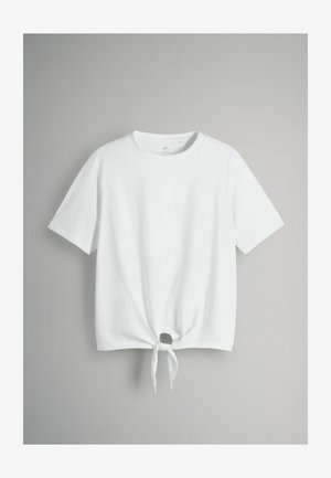 Bela bombažna majica s kratkimi rokavi, ki ima na sprednjem robu zavezano vozlič. Tkanina izgleda gladka in lahka.
