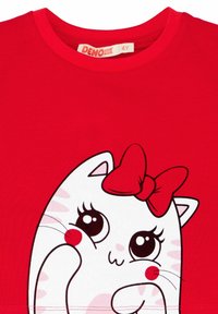 Camiseta de algodón roja con un diseño de un gato de dibujos animados en blanco, con grandes ojos, un lazo y un rubor en las mejillas. Cuello redondeado.