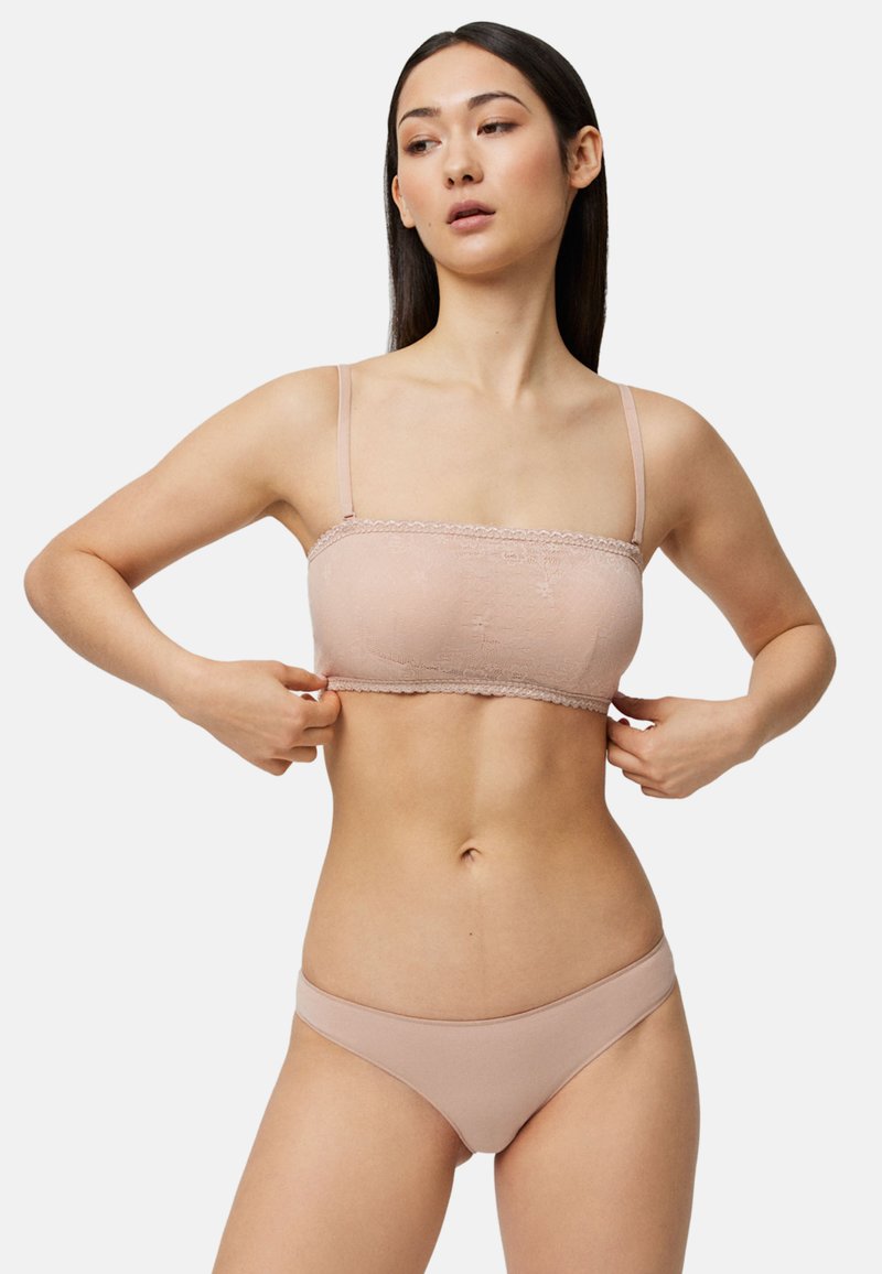 Sostén bandeau color nude con encaje y tirantes ajustables, combinado con bragas de bikini a juego, mostrando una textura de tela suave.