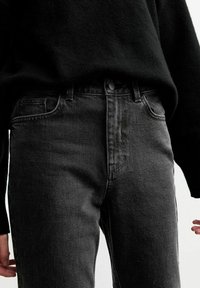 Svarta denimjeans med en figursydd passform, femficksdesign och en subtil blekningseffekt. Har en knappstängning och bältesöglor.