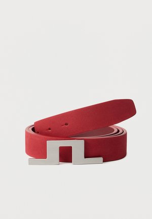 Rode leren riem opgerold met een zilveren geometrische gesp op een witte achtergrond.