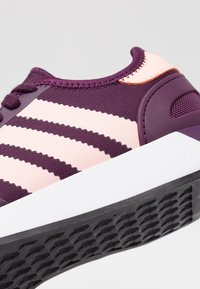 Lila sneakers med ljusrosa ränder, övre i mesh och syntetmaterial, vadderat krage och gummerad sula för bra grepp.