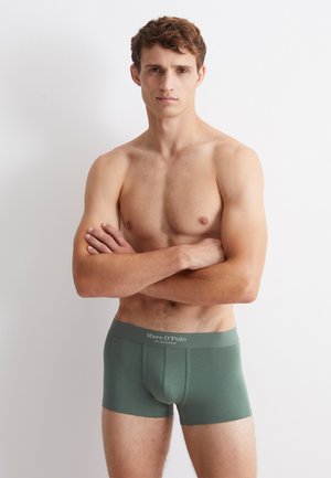 Boxers-briefs verts en tissu doux, avec une ceinture confortable portant le logo "Marc O'Polo" et un design ajusté, présentés sur un modèle masculin.