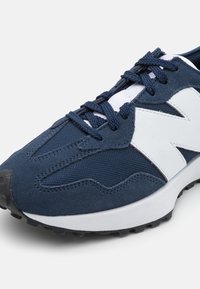 Chaussure de sport bleue avec une tige en maille bleu marine ornée d'accents en suède, un logo blanc et une semelle en caoutchouc noir texturé.