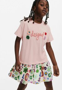 Ljust rosa T-shirt med broderad "desigual" text och blommönster. Lagerpassad kjol med färgglada blommor och bokstäver. Avslappnad passform.