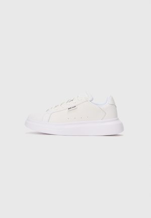 Zapatilla blanca de corte bajo con suela gruesa, diseño con cordones y pequeño logo "just cavalli" en el lateral sobre un fondo liso.