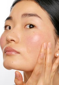 Gel trasparente applicato sulla guancia, che rivela una carnagione liscia e radiosa con una texture della pelle naturale e un effetto di leggera rossore.