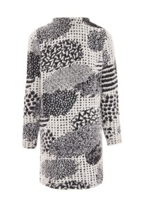 Dlouhý, oversized svetr v bílé barvě s černými abstraktními vzory. Měkká textura, kulatý výstřih a dlouhé rukávy. Lem končí v polovině stehna.