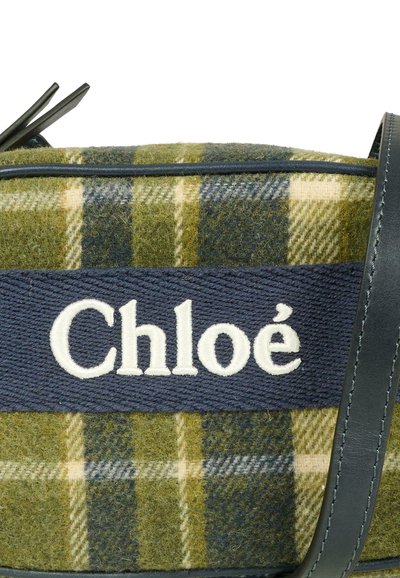 Borsa in tessuto scozzese verde con una fascia in tessuto blu scuro e testo ricamato bianco "Chloé" e dettagli in pelle scura.