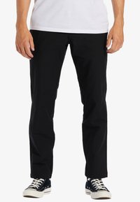 Sorte bomuldsbukser med lige pasform, der har sidelommer, minimal syning og er parret med sort-hvide sneakers.