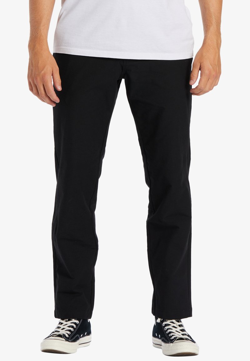 Sorte bomuldsbukser med lige pasform, der har sidelommer, minimal syning og er parret med sort-hvide sneakers.