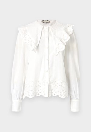 Valge pluus kõrge krae, volangäärise ja lillemustriga lõigatud pitsdetailidega allosas. Nupuga esiosa ja pikad varrukad.