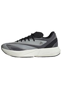Buty sportowe w kolorze szarym i czarnym, charakteryzujące się eleganckim designem, gładką syntetyczną cholewką, siateczkowymi akcentami i lekką piankową podeszwą środkową oznaczoną "LIGHTSTRIKE."