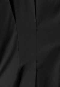 Tissu noir avec des coutures de couture verticale et de légers plis créant des effets de texture et d'ombre.