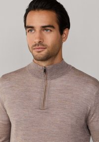  Lichtbruine zip-up trui met hoge kraag, gemaakt van gestructureerde stof, met een subtiel patroon en een contrasterende rits.