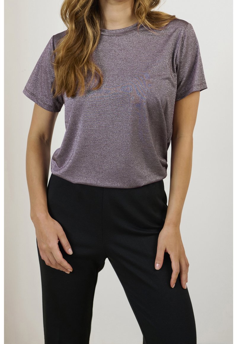 Glänsande lila t-shirt med kort ärm och rund halsringning, kombinerad med svarta byxor. Tyget har en texturerad lyster.